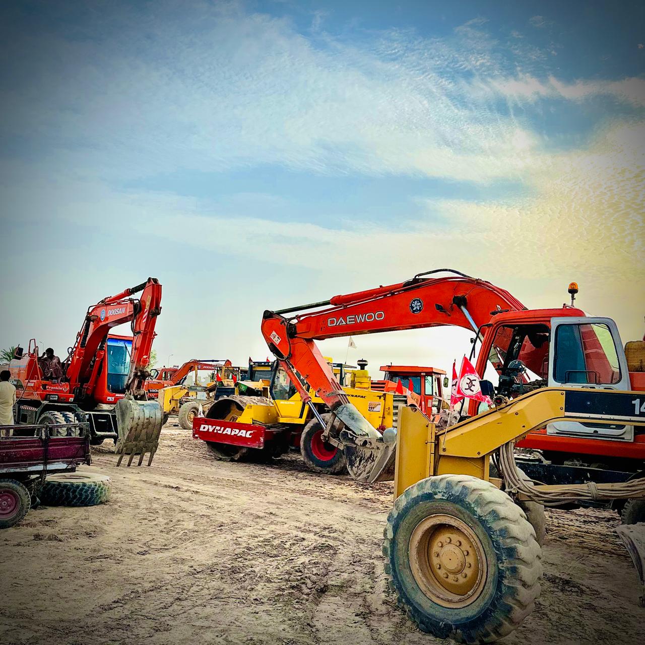 Heavy equipment yard with multiple excavators, a Dynapac roller, and a grader parked on site